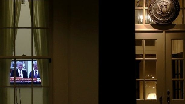 A television plays a news report on U.S. President Donald Trump's recent Oval Office meeting with Russia's Foreign Minister Sergei Lavrov as night falls on offices and the entrance of the West Wing White House in Washington, U.S. May 15, 2017.  REUTERS/Jonathan Ernst     TPX IMAGES OF THE DAY - RTX35ZV9