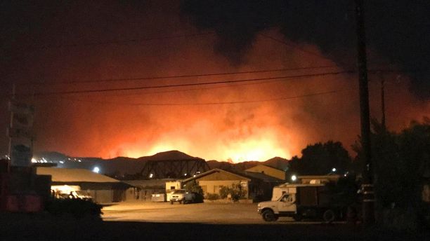 Flames from a wildfire loom up over a neighborhood in Santa Paula, Calf., Monday, Dec. 4, 2017. Ventura County fire officials say the blaze broke out Monday east of Santa Paula, a city of 30,000 people about 60 miles northwest of downtown Los Angeles. Powerful winds are pushing the blaze west toward the city along Highway 150, which is shut down. (Megan Diskin/The Ventura County Star via AP)