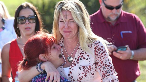 Dos mujeres lloran tras el reporte de un tiroteo en la Escuela Secundaria Marjory Stoneman Douglas de Parkland, Florida, el miércoles 14 de febrero de 2018. (AP Foto/Joel Auerbach)