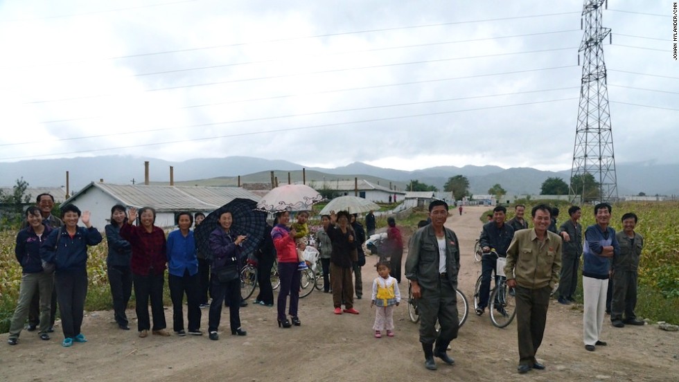 Peasants and villagers standing by the road to look at the Western cyclists