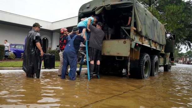 Volunteers load people into a collector's vintage military truck to evacuate them from flood waters from Hurricane Harvey in Dickinson, Texas, U.S. August 27, 2017. REUTERS/Rick Wilking - RTX3DL7S