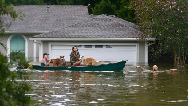 A family evacuates their Meyerland home in Houston, Sunday, Aug. 27, 2017. Rescuers answered hundreds of calls for help Sunday as floodwaters from the remnants of Hurricane Harvey rose high enough to begin filling second-story homes, and authorities urged stranded families to seek refuge on their rooftops. (Mark Mulligan/Houston Chronicle via AP)
