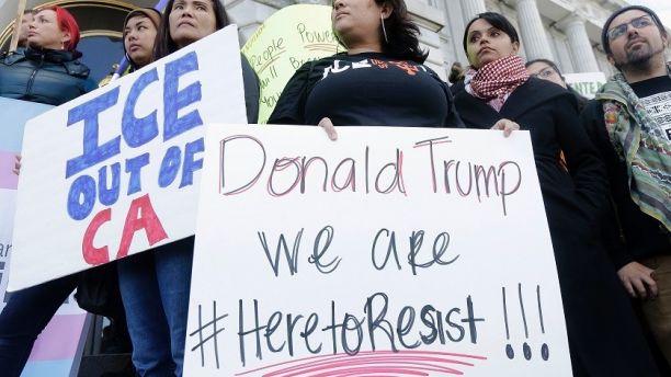 In this Jan. 25, 2017 file photo protesters hold signs as they listen to speakers at a rally outside of City Hall in San Francisco, Calif. California Gov. Jerry Brown signed legislation, SB54, the statuary state bill, that extends protections statewide for immigrants living the United State illegally, Thursday, Oct. 5, 2017. (AP Photo/Jeff Chiu,file)