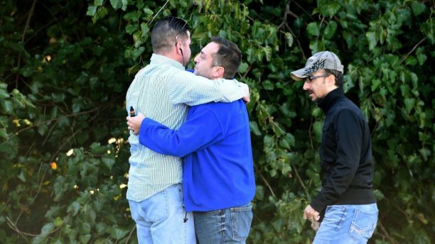 Unidentified bystanders embrace as police and Emergency Medical Services respond to a shooting at a business park in the Edgewood area of Harford County, Md., Wednesday, Oct. 8, 2017. (Matt Button/The Baltimore Sun via AP)