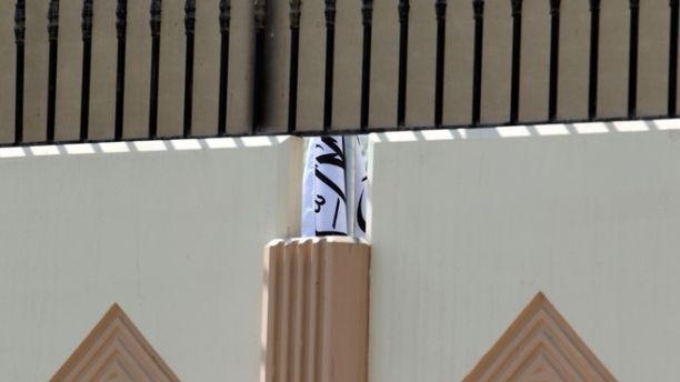 This photo taken on Thursday, June 20, 2013 shows the Taliban flag visible through a gap in a wall of the new office of the Afghan Taliban in Doha, Qatar after the opening of the office. 