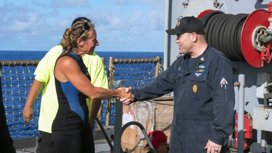 In this Wednesday, Oct. 25, 2017 photo, USS Ashland Command Master Chief Gary Wise welcomes aboard Jennifer Appel, an American mariner, one of two Honolulu women and their dogs who were rescued after being lost at sea for several months while trying to sail from Hawaii to Tahiti.