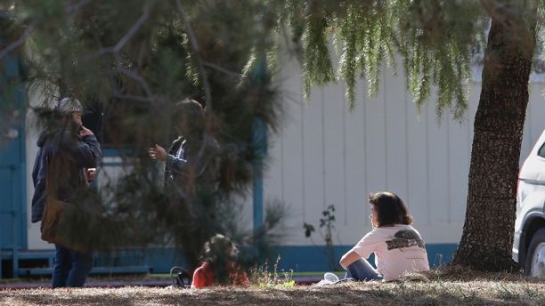 A woman and a child sit by an elementary school where a gunman opened fire in the community of Rancho Tehama Reserve in Corning, Calif., Tuesday, Nov. 14, 2017. The gunman choosing targets at random opened fire in the rural Northern California town Tuesday, killing several people at several sites and wounding others at the elementary school before police shot him dead, authorities said. (AP Photo/Rich Pedroncelli)