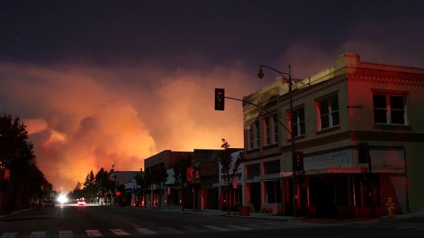 Downtown is darkened by a power outage with smoke rising in the distance as strong winds push the Thomas Fire across thousands of acres in Santa Paula, California, U.S., December 5, 2017.      REUTERS/David McNew - RC1B63D603D0