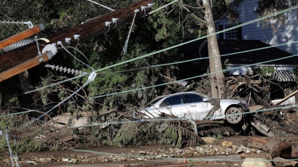 A damaged car sits over fallen and debris behind downed power lines in Montecito, Calif., Wednesday, Jan. 10, 2018. Dozens of homes were swept away or heavily damaged and several people were killed Tuesday, as downpours sent mud and boulders roaring down hills stripped of vegetation by a gigantic wildfire that raged in Southern California last month. (AP Photo/Marcio Jose Sanchez)