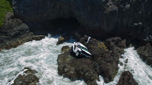 In this May 30, 2016 photo provided by Tom Johnson, a vehicle sits at the bottom of a cliff off Maui's Hana Highway in Hana, Hawaii. Alexandria Duval, who is also known as Alison Dadow, was driving the vehicle when it plunged off the Maui cliff May 29, and is charged with second-degree murder in the death of her twin, Anastasia Duval, also known as Ann Dadow, who was in the passenger's seat. (Tom Johnson via AP) MANDATORY CREDIT