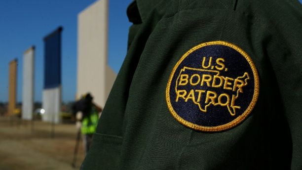 A border patrol officer stands next to some of U.S. President Donald Trump's eight border wall prototypes as they near completion along U.S.- Mexico border in San Diego, California, U.S., October 23, 2017. REUTERS/Mike Blake - RC1132098000