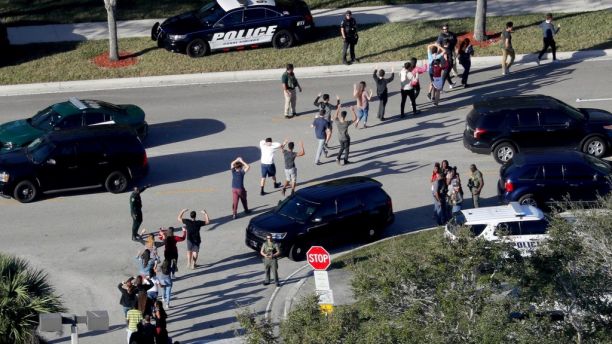 FILE - In this Wednesday, Feb. 14, 2018 file photo, students hold their hands in the air as they are evacuated by police from Marjory Stoneman Douglas High School in Parkland, Fla., after a shooter opened fire on the campus. A week after a shooter slaughtered more than a dozen people in the Florida high school, thousands of protesters, including many angry teenagers, swarmed into the state Capitol on Wednesday, Feb. 21, calling for changes to gun laws, a ban on assault-type weapons and improved care for the mentally ill. (Mike Stocker/South Florida Sun-Sentinel via AP, File)