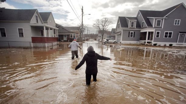 Kaylee Collin, right, and Spencer Stone walk through water along North Avenue in Camp Ellis in Saco, Maine on Sunday, March 4, 2018. The coastal neighborhood as well as other parts of the southern Maine coast were flooded for the third day in a row on Sunday. (Gregory Rec/Portland Press Herald via AP)