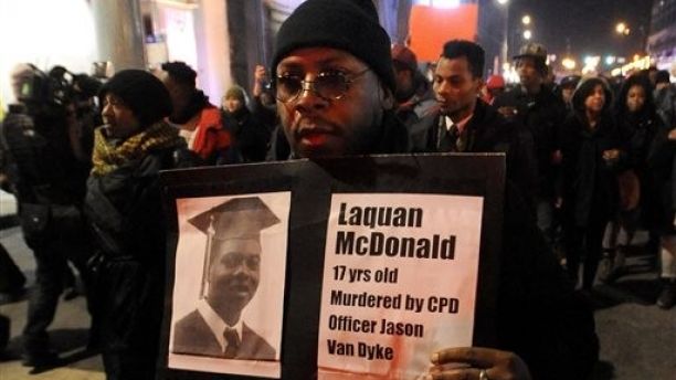 FILE - In this Tuesday, Nov. 24, 2015, file photo, a protester holds a sign as people rally for 17-year-old Laquan McDonald, who was shot 16 times by Chicago Police Department Officer Jason Van Dyke in Chicago. McDonald, whose name demonstrators are shouting as they march the streets and plan to shut down the citys glitziest shopping corridor on Friday, lived a troubled life full of disadvantages and at least one previous brush with the law. (AP Photo/Paul Beaty, File)